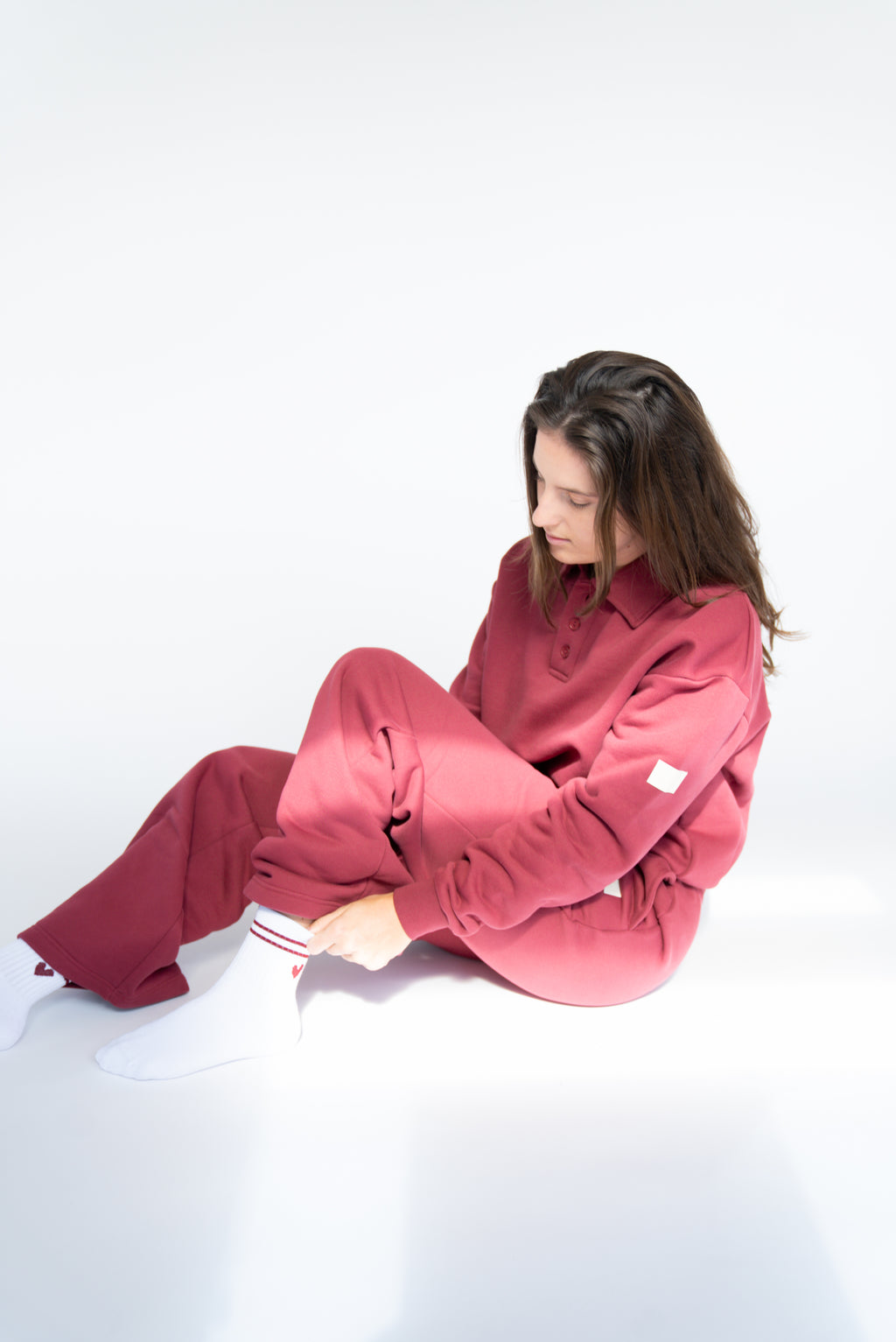Lavoréa Everyday Socks in Burgundy, seated while pulling the sock into place