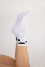 Lavoréa Pilates Grip Socks in Black, single foot raised with the silicone grip along the sole